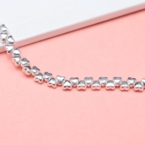 S925 sterling silver heart-shaped spacer beads for bracelets on a pink background