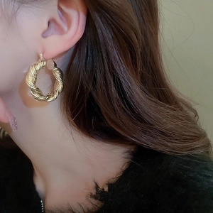 Vintage hollow waterdrop earrings in gold twist design worn by a female model