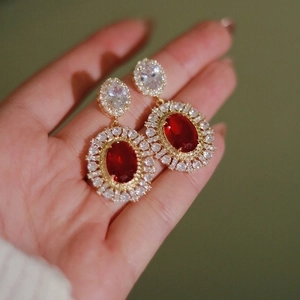 Vintage palace style earrings with red oval gemstone and white zircon halo in gold finish