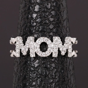 Macro shot of silver MOM letter ring with pavé sparkling crystals on a black stand