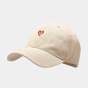 Beige minimalist baseball cap with red heart embroidery and canvas fabric texture