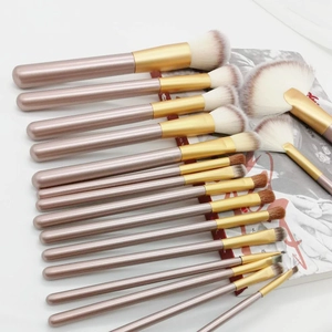 Set of 15 professional makeup brushes with rose gold handles on a white background