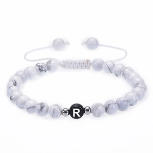 Vue macro de perles en howlite 6mm et perle lettre R sur bracelet tressé réglable blanc
