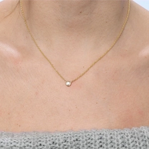Minimalist gold-plated necklace with a round zircon pendant worn by a model