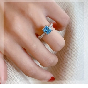 Minimalist square blue zircon ring on model's finger with shimmering side diamonds