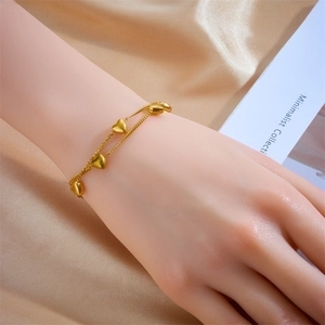 Minimalist double layer chain bracelet with gold heart charms for women on silk background