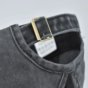 Detail of adjustable brass buckle on vintage washed grey cotton ponytail baseball cap