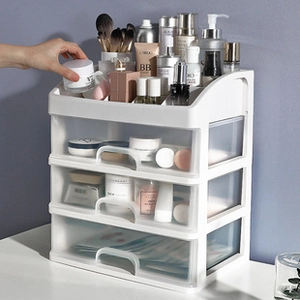 Cosmetic organizer with three transparent drawers and top tray in use on a white desk