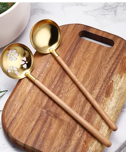 Detail of gold SUS304 stainless steel soup and slotted spoons with beech wood handles