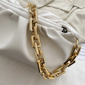 Detailed close-up of white ruched leather handbag featuring a chunky gold chain strap