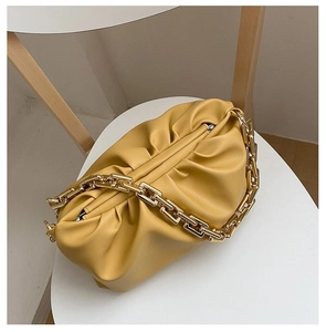 Detailed shot of yellow cloud-shaped handbag with premium chunky gold chain on chair