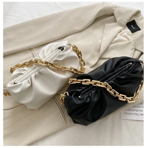 Detail of soft pleated cloud bags in beige and black with thick gold chain straps