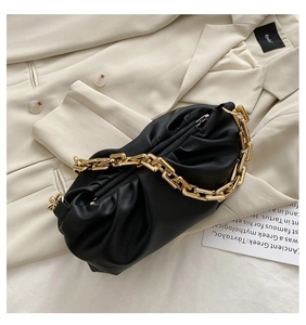 Detail of black cloud pleated handbag with chunky gold chain strap on blazer