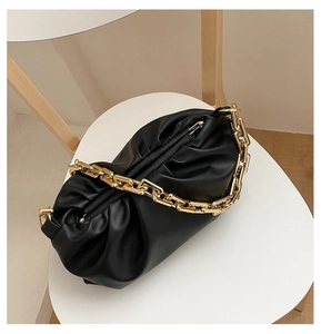 Close-up of black leather dumpling bag with textured pleats and chunky gold chain strap