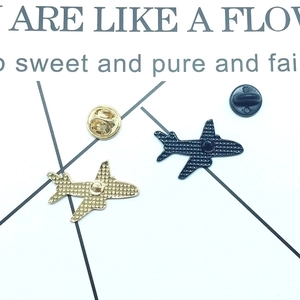 Golden and black airplane pins showing textured metallic back details and secure clasps