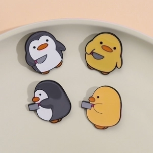 Cute penguin and duck enamel pin set with knives displayed on a ceramic tray
