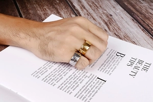 Detail showing the hammered texture on wide stainless steel rings in gold and silver