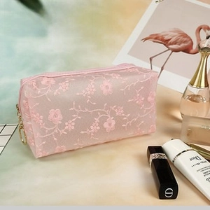 Detailed embroidery on pink mesh makeup bag with golden zipper and floral lace patterns