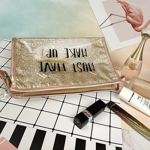 Detail of gold glitter makeup bag featuring black Must Have Make Up lettering
