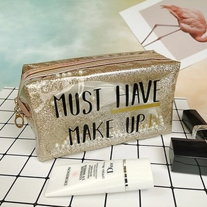 Detail of gold glitter makeup bag featuring a transparent window with pearl accents