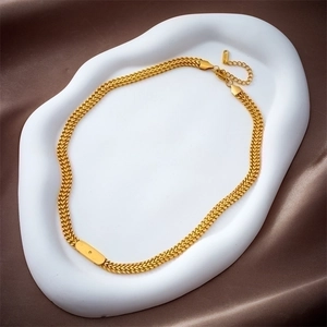 Vintage gold woven chain necklace with a rectangular metal plaque on a white display base