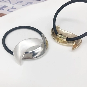 Detailed view of curved gold and silver metal moon-shaped ponytail holders on black elastic