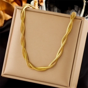 Dettaglio macro di una collana a catena serpente intrecciata placcata oro su base beige