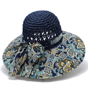 Close-up of navy straw sun hat with paisley print wide brim and decorative bow detail