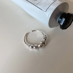 Macro shot of minimalist S925 sterling silver beaded ring on a soft cream background