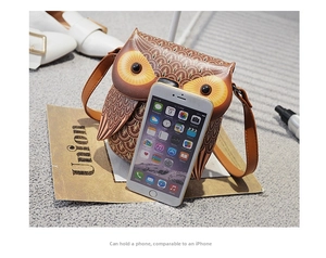 Detail view of owl cross-body bag capacity showing it fits a standard smartphone