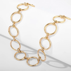 Détail du collier à cercles métalliques dorés entrelacés avec un fermoir en T classique