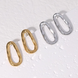 Minimalist irregular oval earrings with gold and silver lava texture on white background