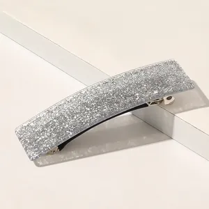 Vue détaillée d'une pince à cheveux carrée argentée scintillante sur socle