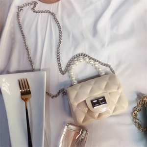 Detail of white quilted mini jelly bag with pearl handle and silver chain strap