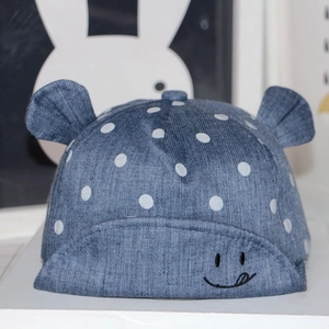 Close-up of blue baby baseball cap with white polka dots and smiling face embroidery