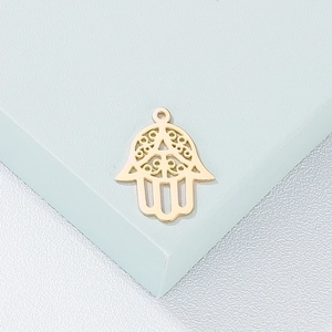 Detailed view of a golden hollow Hamsa pendant on a green geometric block