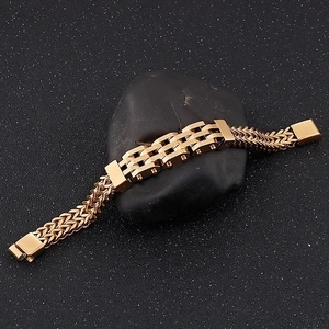 Men's double-row gold titanium steel bracelet shown on a black pebble stone
