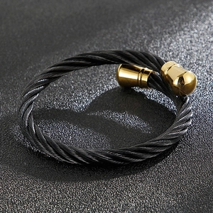 Macro detail of black twisted cable cuff bracelet with polished gold bullet ends