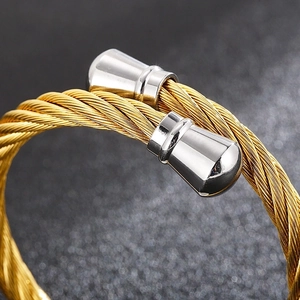 Macro detail of the twisted cable texture and silver cone tips on a gold C-shape bracelet