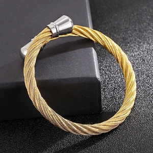 Close-up of gold twisted wire bangle with silver metal end caps on a black surface