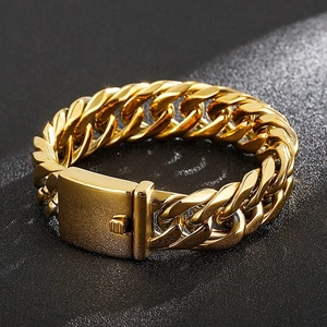 Close-up of a polished gold Cuban link bracelet with a secure box clasp on a dark background