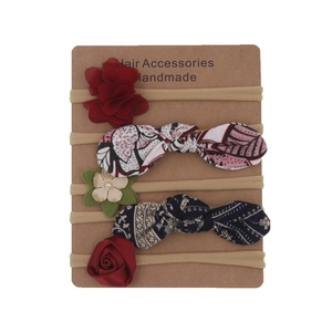 Detailed set of 5 elastic baby headbands with flowers and bows on a paper display card