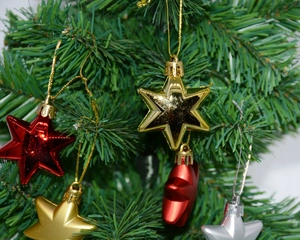 Three-dimensional Christmas star ornaments in red, gold, and silver on a green tree