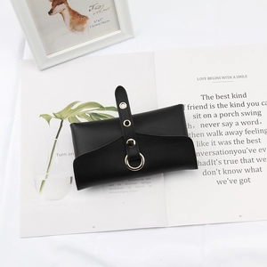 Detail of matte black leather eyewear pouch with metallic grommets on a magazine