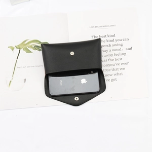 Detail of a black leather belt pouch with a smartphone inside on a desk setup