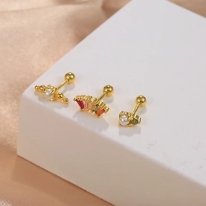 Macro shot of gold S925 silver stud earrings with pearls and colored zircons on silk
