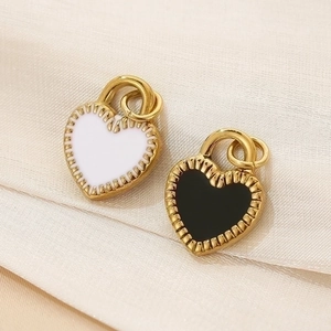 Detailed close-up of heart-shaped pendants with black and white enamel in gold finish