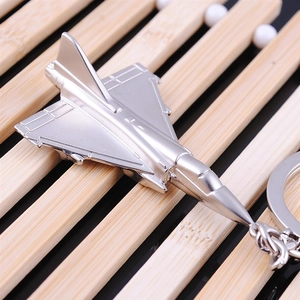 Silver fighter jet model keychain with durable metal ring on bamboo background