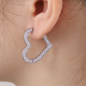 Close-up of silver hollow heart earring with pavé cubic zirconia on a female model's ear