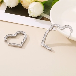 Detail of silver heart hoop earrings with micro-inlaid cubic zirconia on a soft background